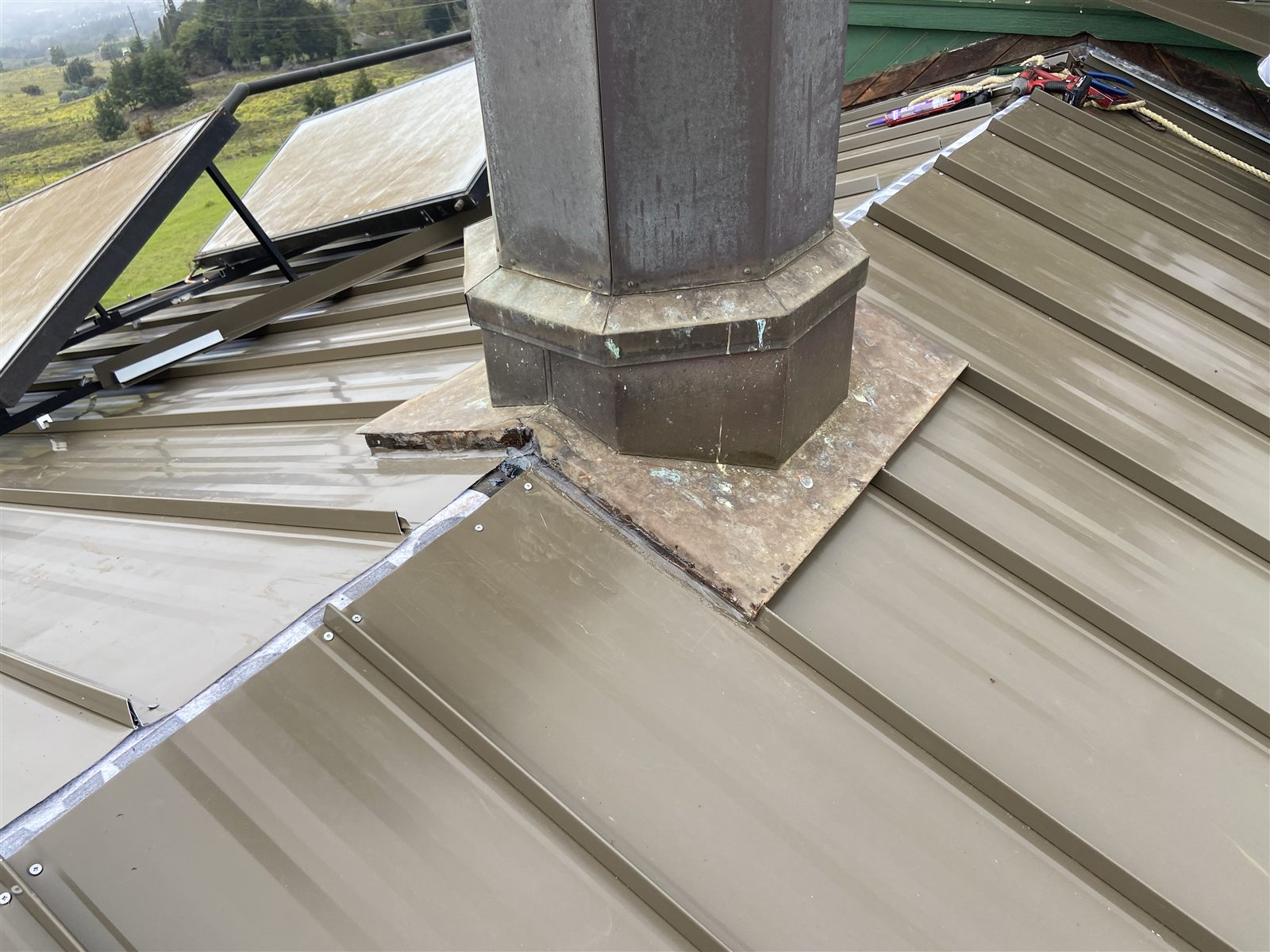 Custom copper chimney flashing on a bronze standing seam roof
