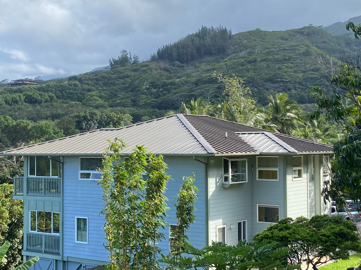 Completed metal roof on a two-story home against the West Maui mountains